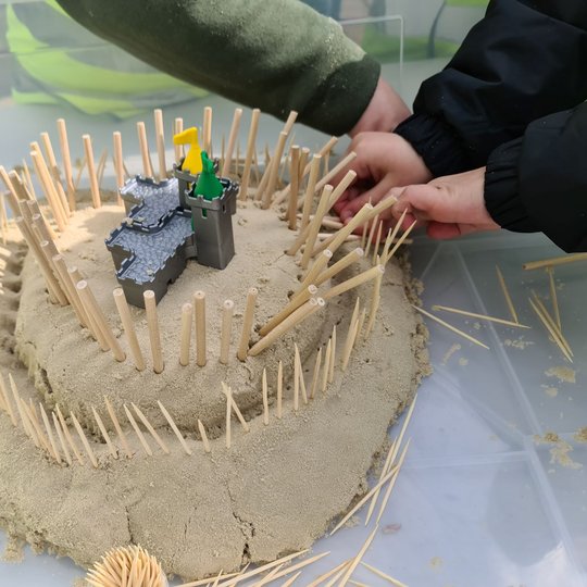 Viena iš mokinių pastatytų smėlio pilių. Į ją susmaigstyti pieštukai - vaizduoja fortifikacijas.