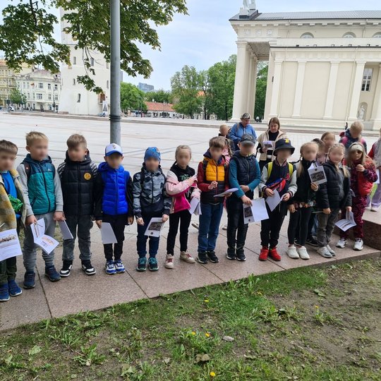 Mokiniai išsirikiavę Katedros aikštės pietiniame skvere, prie gynybinės sienos fragmentų.