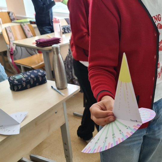 Berniukas rankoje laiko savo pagamintą saulės laikrodį.