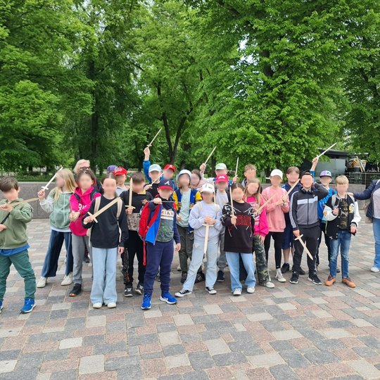 Mokinių grupė Katedros aikštėje. Jie rankose turi medinius kardus.