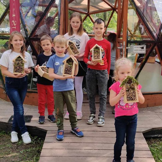Vaikai prie Vilniaus pilių kupolo rodo savo dekoruotus inkilėlius.