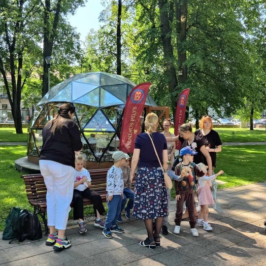 Žmonių grupė ant suoliuko, prie Vilniaus pilių kupolo.