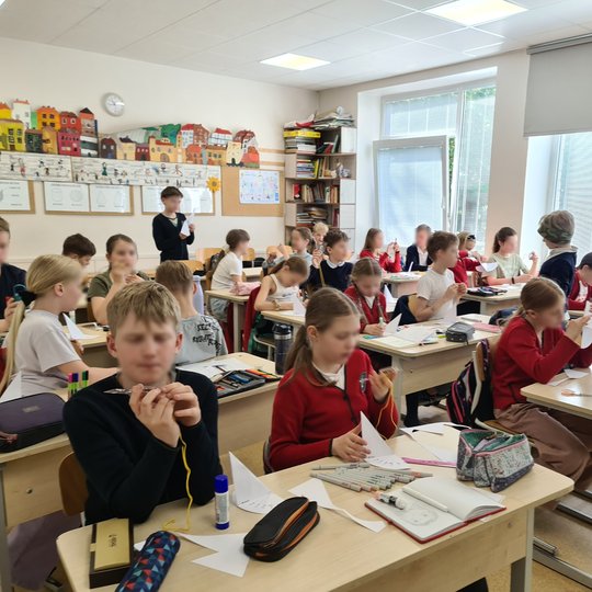 Vaikai klasės suoluose tyrinėja kompasus.
