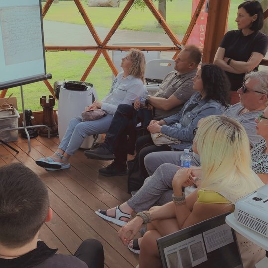 Grupė žmonių sėdi Vilniaus pilių kupole ir žiūri į paskaitos prezentaciją.