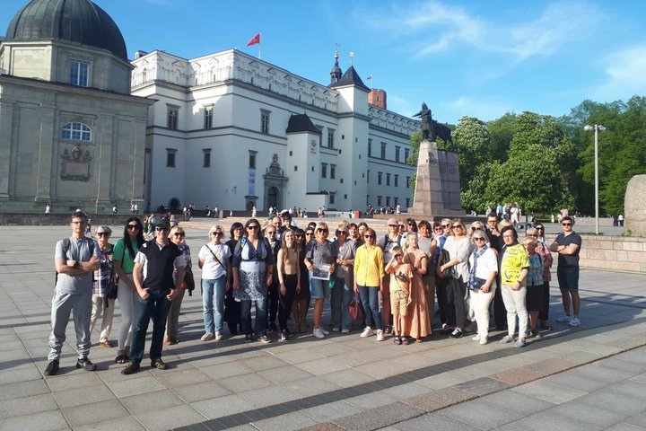 Gausi grupė ekskursijos dalyvių Katedros aikštėje. Jie apšviesti vakarinės saulės.
