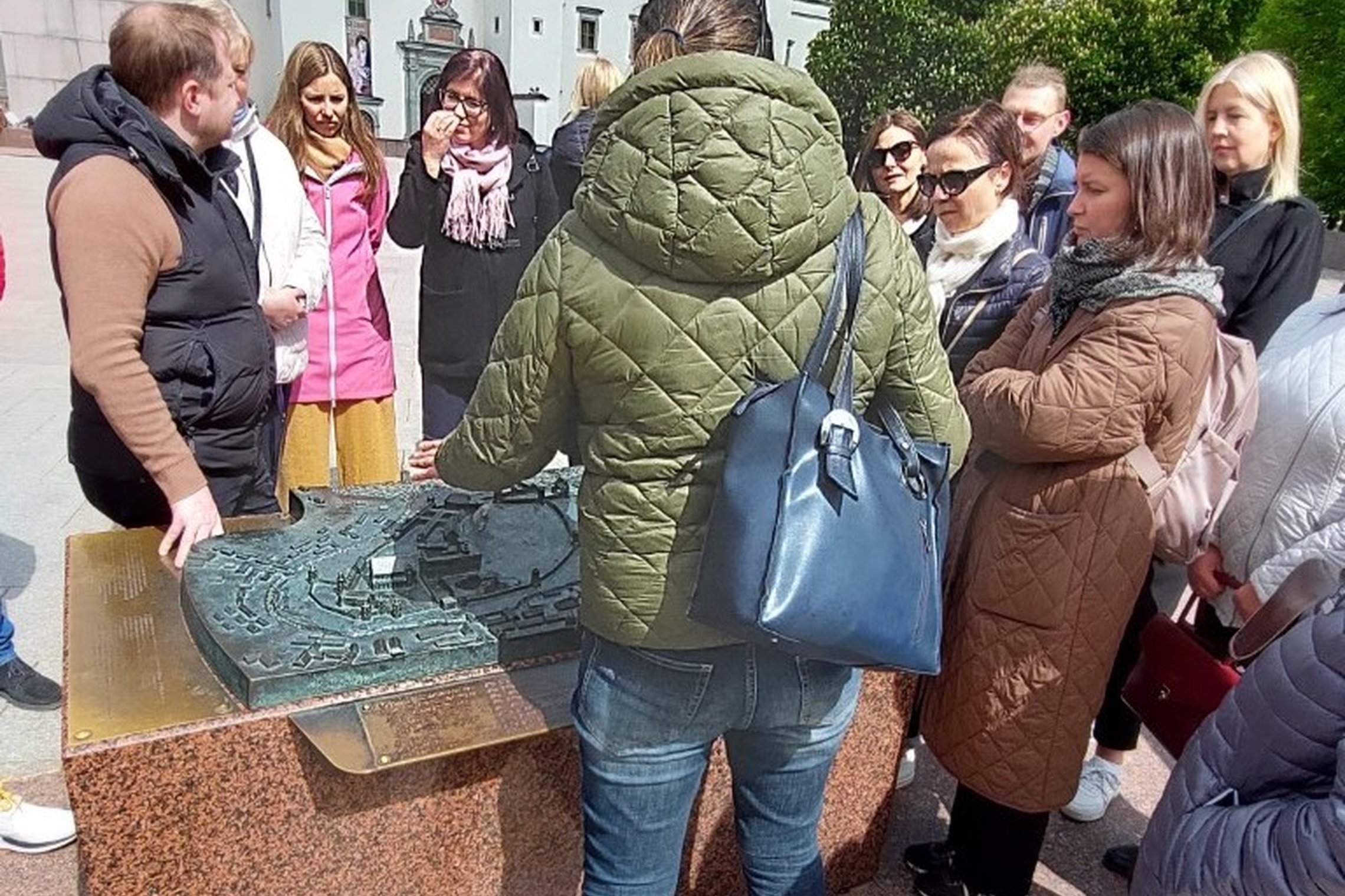 Gidė su ekskursijos dalyviais prie metalinio Vilniaus pilių maketo.