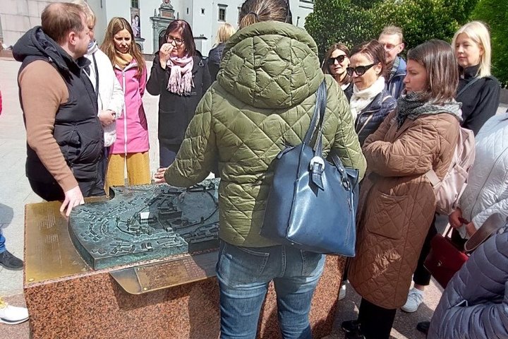 Gidė su ekskursijos dalyviais prie metalinio Vilniaus pilių maketo.