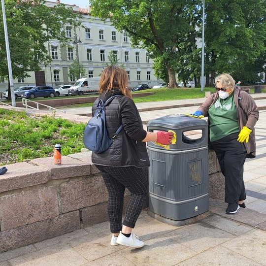 Dvi savanorės valo šiukšliadėžę Katedros aikštėje, prie Gedimino paminklo.