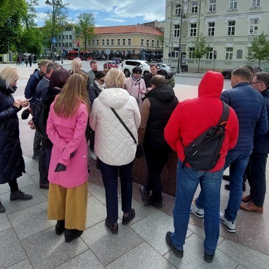 Gidė su ekskursijos dalyviais prie metalinio Vilniaus pilių maketo.
