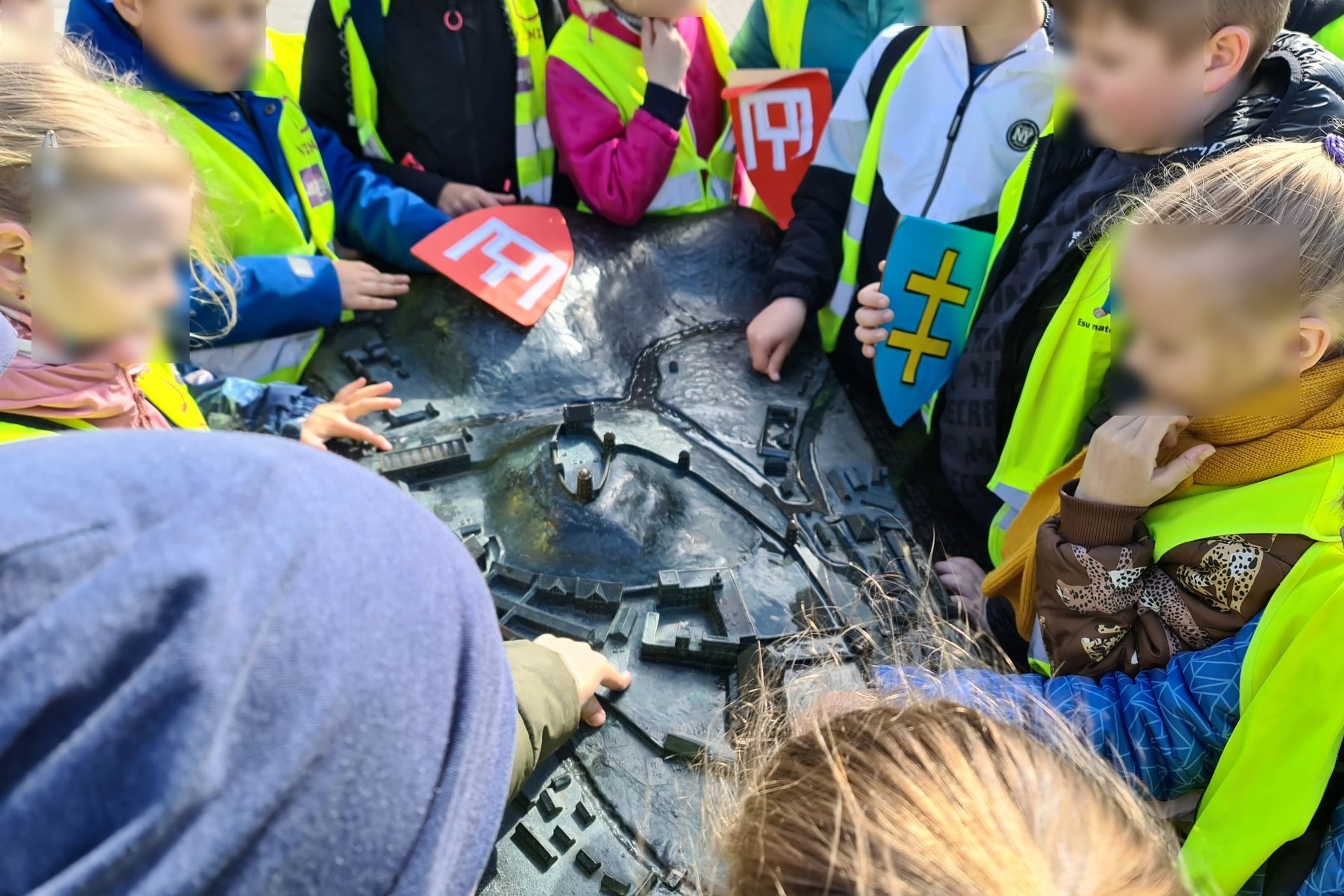 Vaikučiai su atšvaitinėmis liemenėmis ir herbais prie metalinio Vilniaus pilių kupolo.
