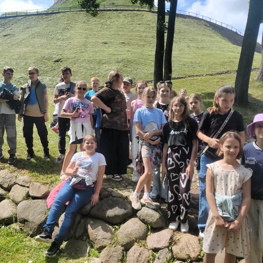 Mokiniai stovi ant Gedimino pilies kalno šlaito.