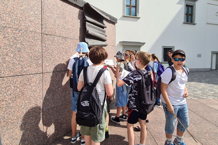Mokiniai Valdovų rūmų kieme tyrinėja Gedimino laiško skulptūrą.