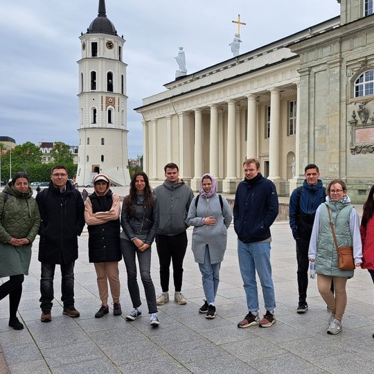 ištvermingiausi savanoriai ekskursijoje su gide stovi prie Gedimino paminklo, Katedros aikštėje.