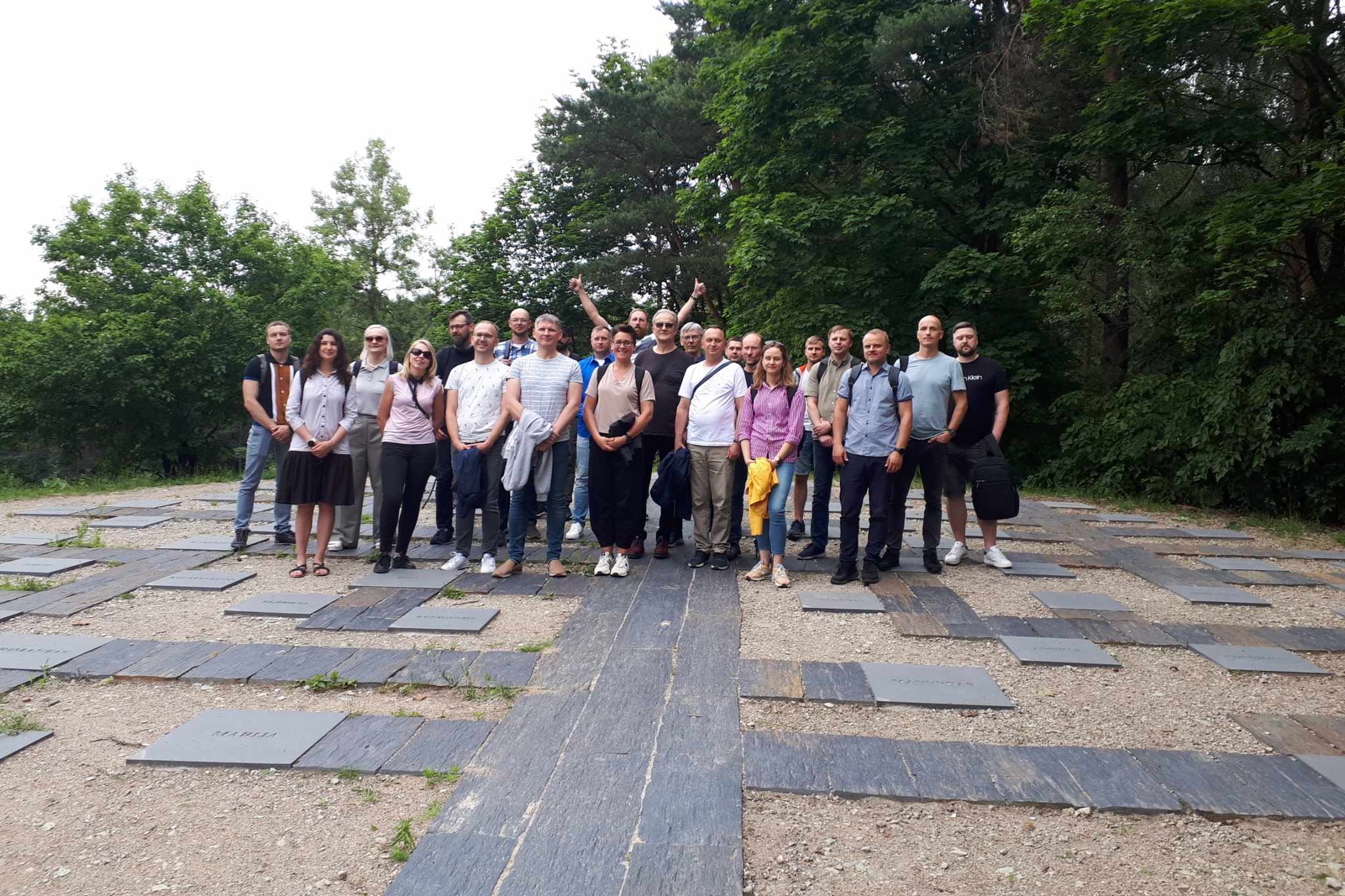 Ekskursijos grupė stovi ant Karigailos kalvos. Gale vienas vyras yra iškėlęs nykščius į viršų.
