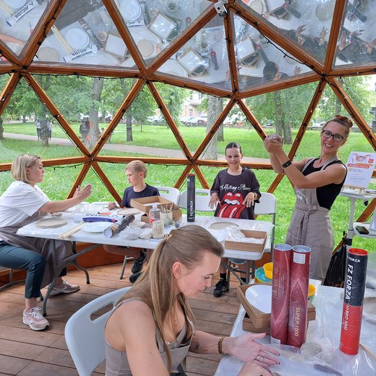 Molininkė kupole, tarp dalyvių, minko molį rankose.