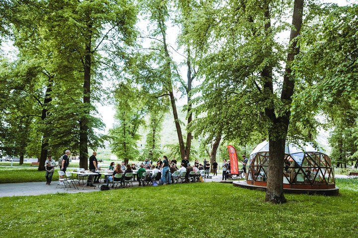 Sereikiškių parke, prie Vilniaus pilių kupolo, sustatyti stalai su kėdėmis, o ant stalų šachmatų žaidimai.