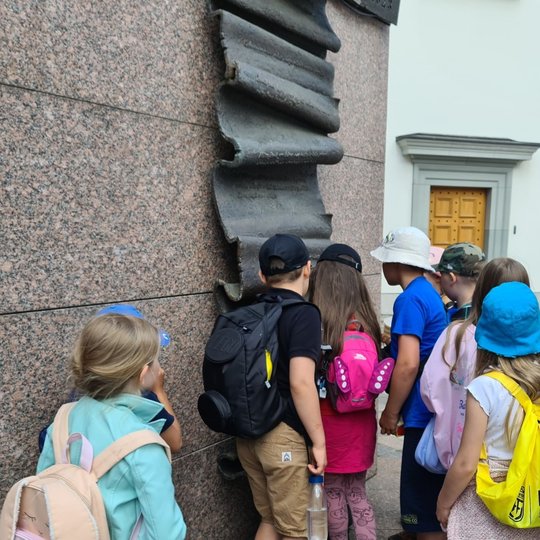 Mokiniai Valdovų rūmų kieme skaito Gedimino laiško skulptūrą.