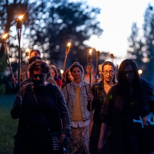 Grupė moterų eina per Kalnų parką su deglais rankose.