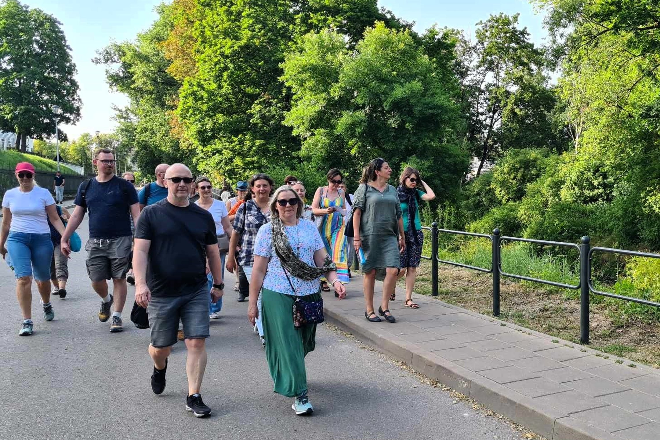 akiniuoti ekskursantai su gide keliauja Vilnios krantu per Sereikiškių parką.