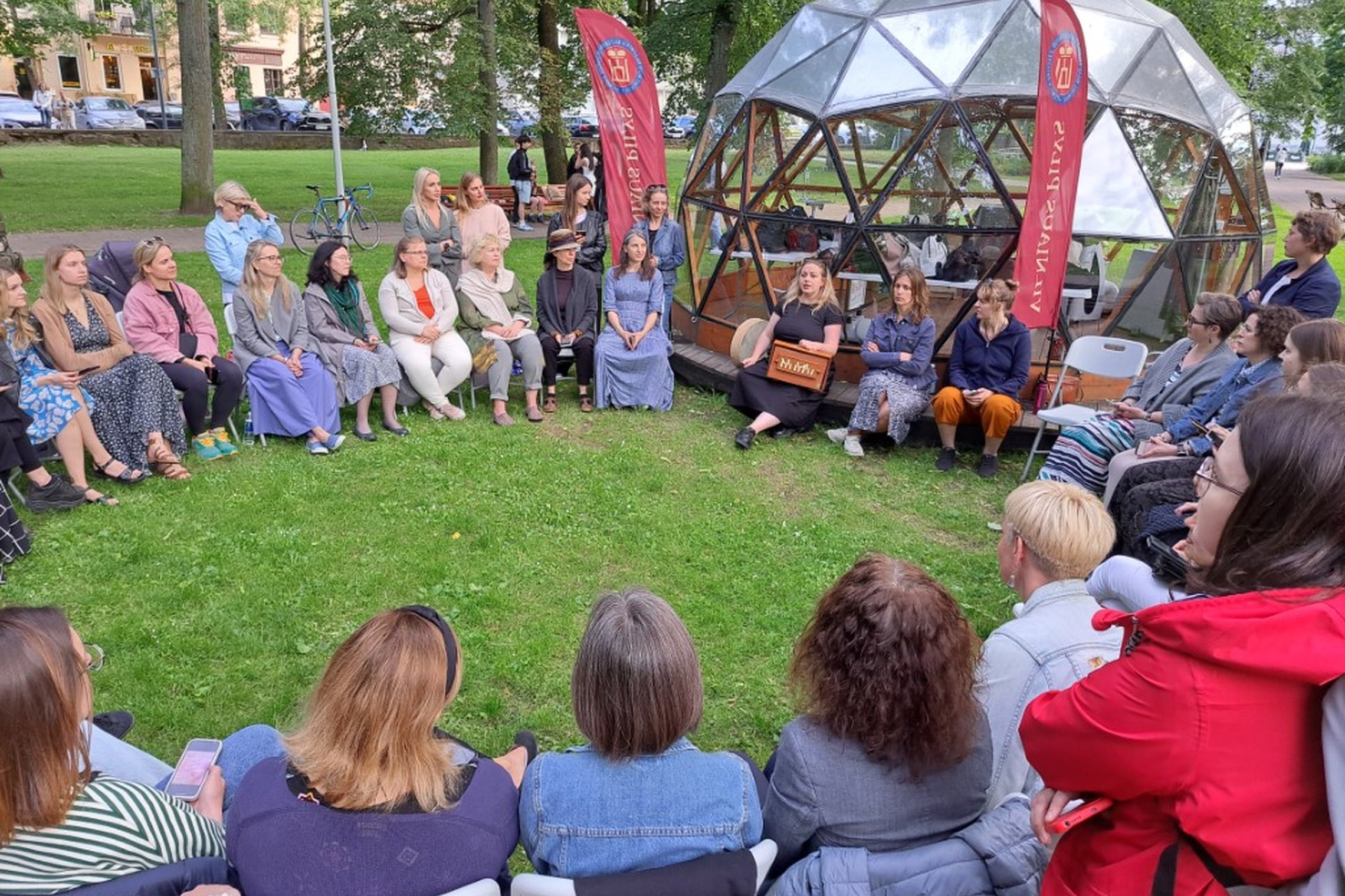 Moterys parke, susėdę ratu prie Vilniaus pilių kupolo.