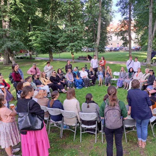 Moterys Sereikiškių parke, sustoję ir susėdę ratu, dainuoja sutartines.