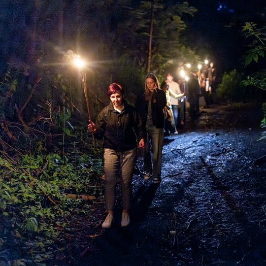 Vorele ekskursantės su deglais  žengia per Didžiąją griovą.