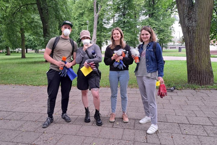 Keturi SEB banko savanoriai, su priemonėmis graffiti valymui, sustoję Sereikiškių parke.