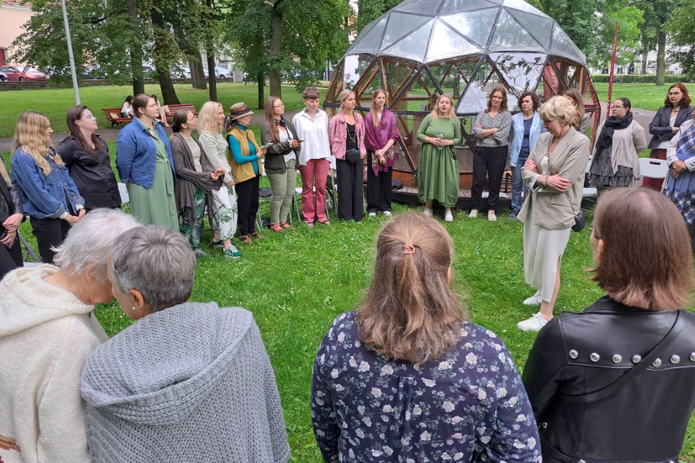 Moterys sustoję ratu prie Vilniaus pilių kupolo dainuoja sutartines.