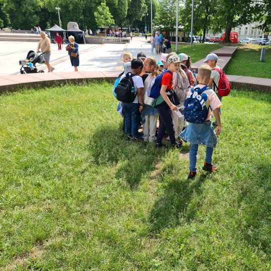 Vaikai būryje Katedros aikštėje, Gynybinio bokšto vietą žyminčių plokščių viduryje.