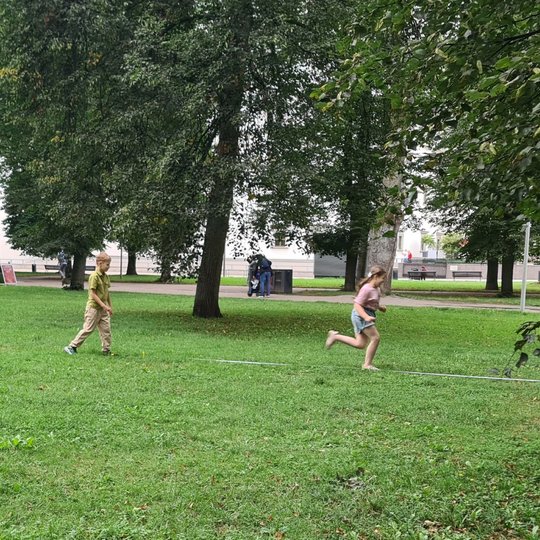 Du vaikai bėga pro ant pievos ištiestą ruletę.