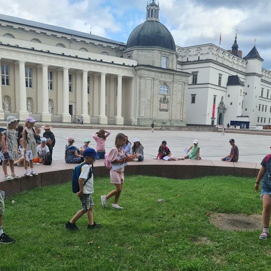 Mokiniai laipioja ant gynybinio bokšto plokščių Katedros aikštėje.