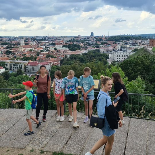 Mokiniai pozuoja priešais senamiesčio panoramą ant Trijų Kryžių kalno.