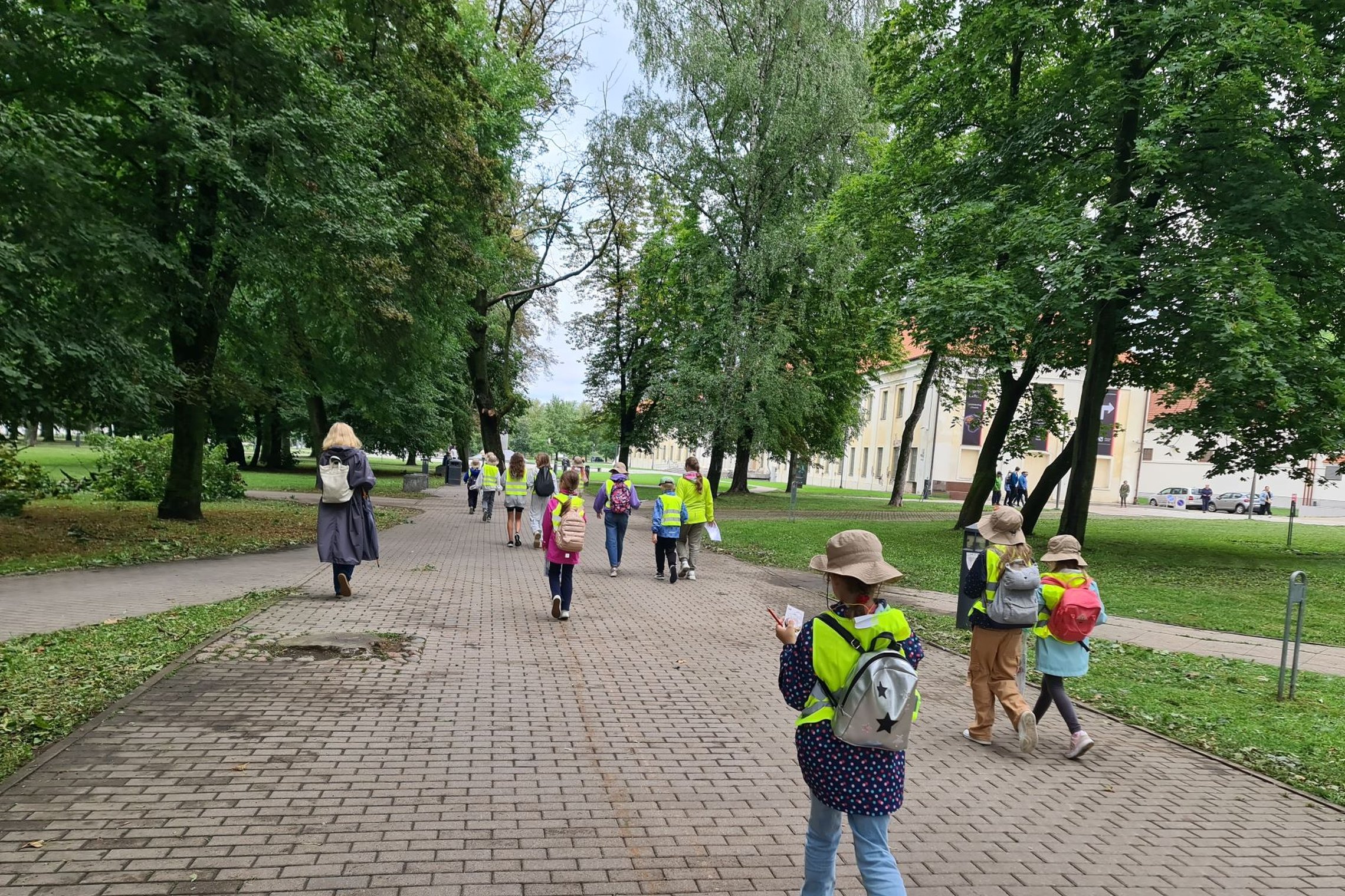 Mindaugo skvero taku einantys vaikai, nufotografuoti iš nugarų.
