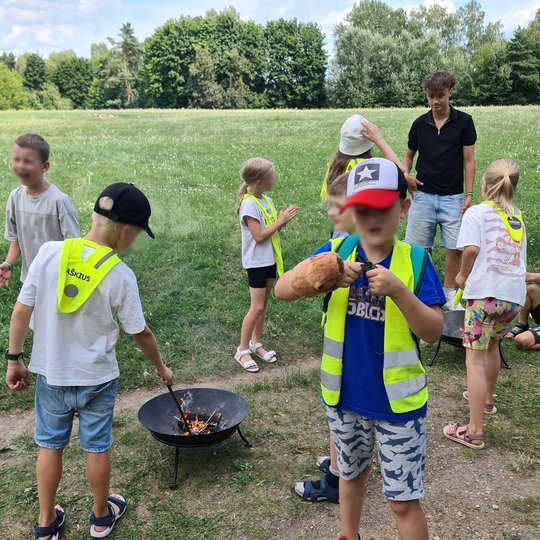 Mokiniai mokosi naudotis skiltuvais ir bando užkurti ugnį laužinėje.