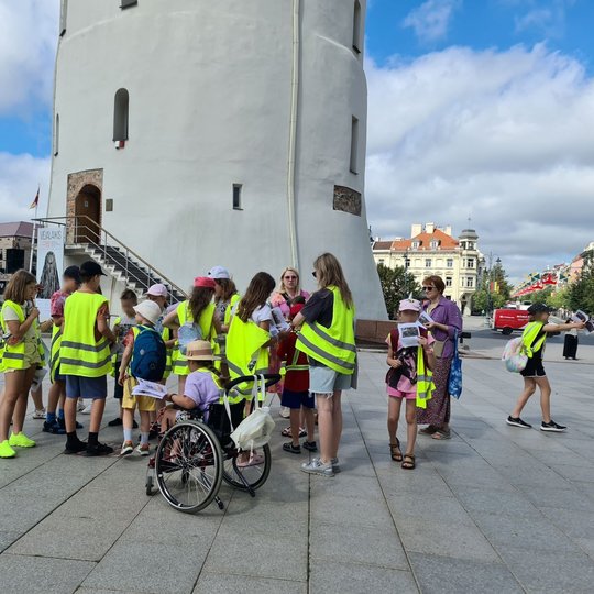 Mokinių grupė prie stebuklingos plytelės Katedros aikštėje.