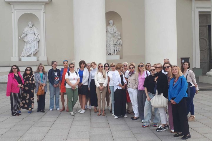 Grupė ekskursantų stovi prie Vilniaus arkikatedros kolonų.