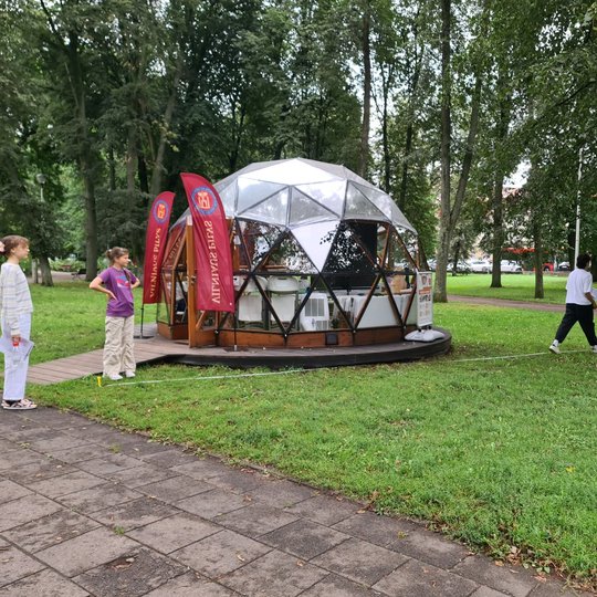 Trys mergaitės matuoja atstumą rulete nuo Vilniaus pilių kupolo iki parko krašto.