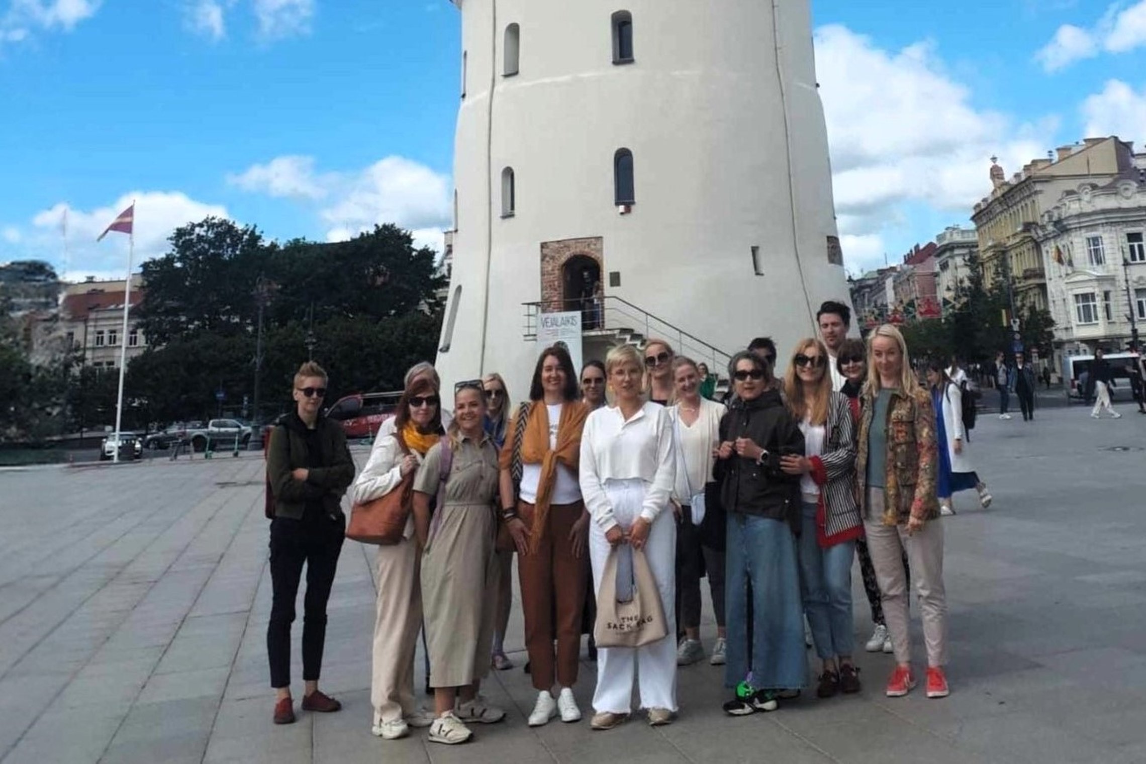 Ekskursantai stovi grupėje, Katedros aikštėje prie varpinės.