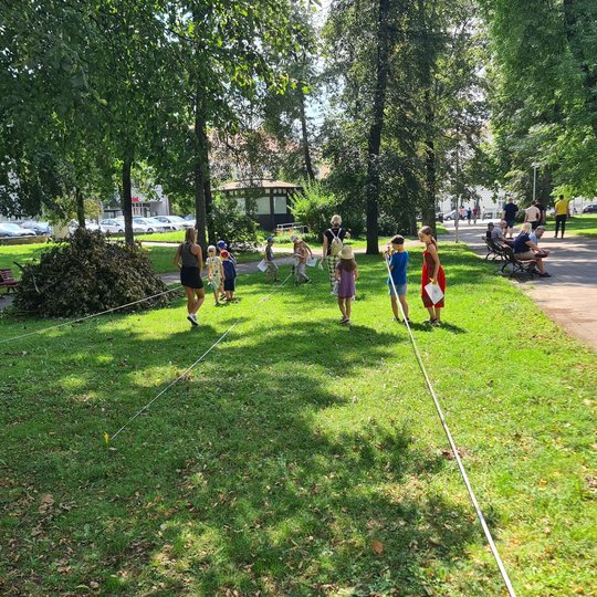 Vaikai matuoja Sereikiškių parką su ištiestomis ruletėmis pievoje.