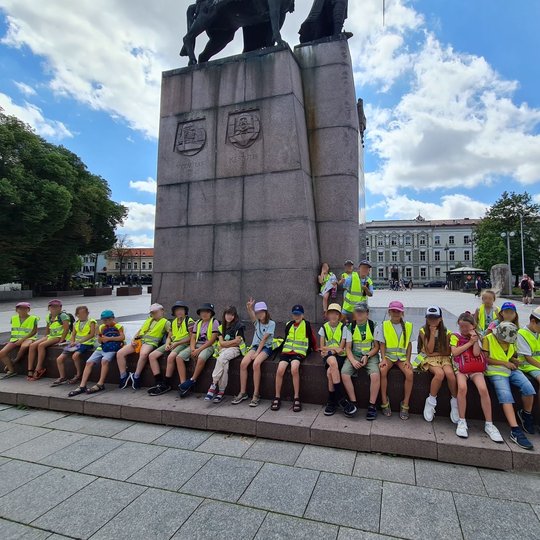 Mokiniai sėdi išsirikiavę ant Gedimino paminklo laiptų Katedros aikštėje.