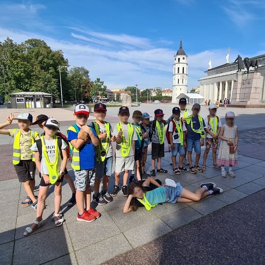 Grupė mokinių Katedros aikštėje, pavėsyje.
