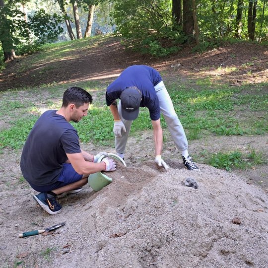 Du vyrai į kibirą semia skaldelę, kuria vėliau užpildys vazonų dugnus.
