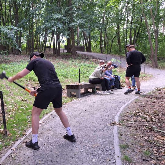 Vyras kala kuolus į žemę su kūju. Už jo kiti savanoriai ilsisi.