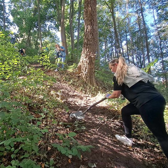 Vyras ir moteris iš dviejų nuotraukos šonų kastuvais purena žemę Trijų Kryžių kalno šlaite.