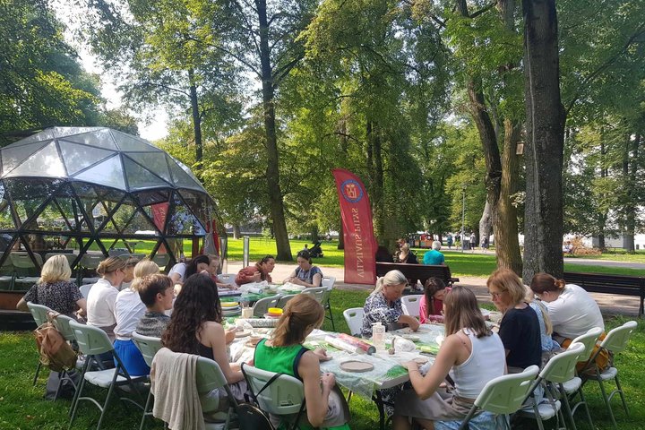 Sereikiškių parke, prie Vilniaus pilių kupolo žmonės sėdi prie stalų ir lipdo molį.