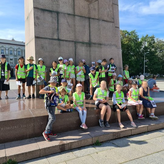 Grupė mokinių pozuoja stovintys ant Gedimino paminklo plokštės.
