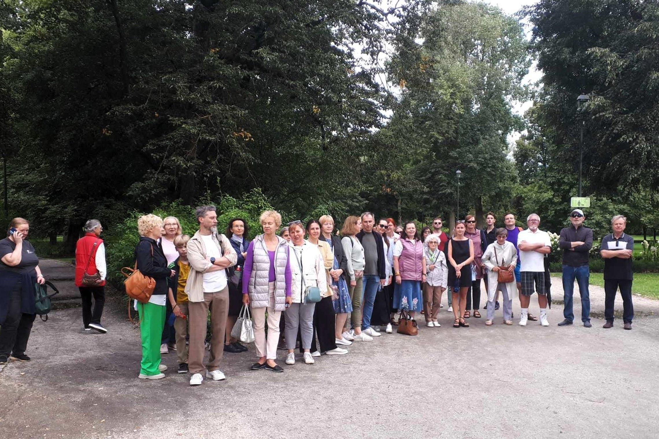 Didelė ir gausi grupė ekskursijos dalyvių stovi Bernardinų sodo take.
