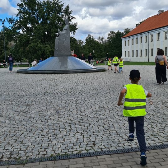 Berniukas bėga Karaliaus Mindaugo paminklo link.