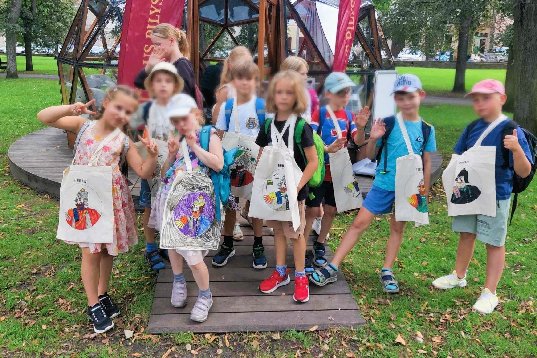 Vienuolika mokinių stovi prie Vilniaus pilių kupolo, ant kaklų užsidėję medžiaginius maišelius su valdovų portretais.