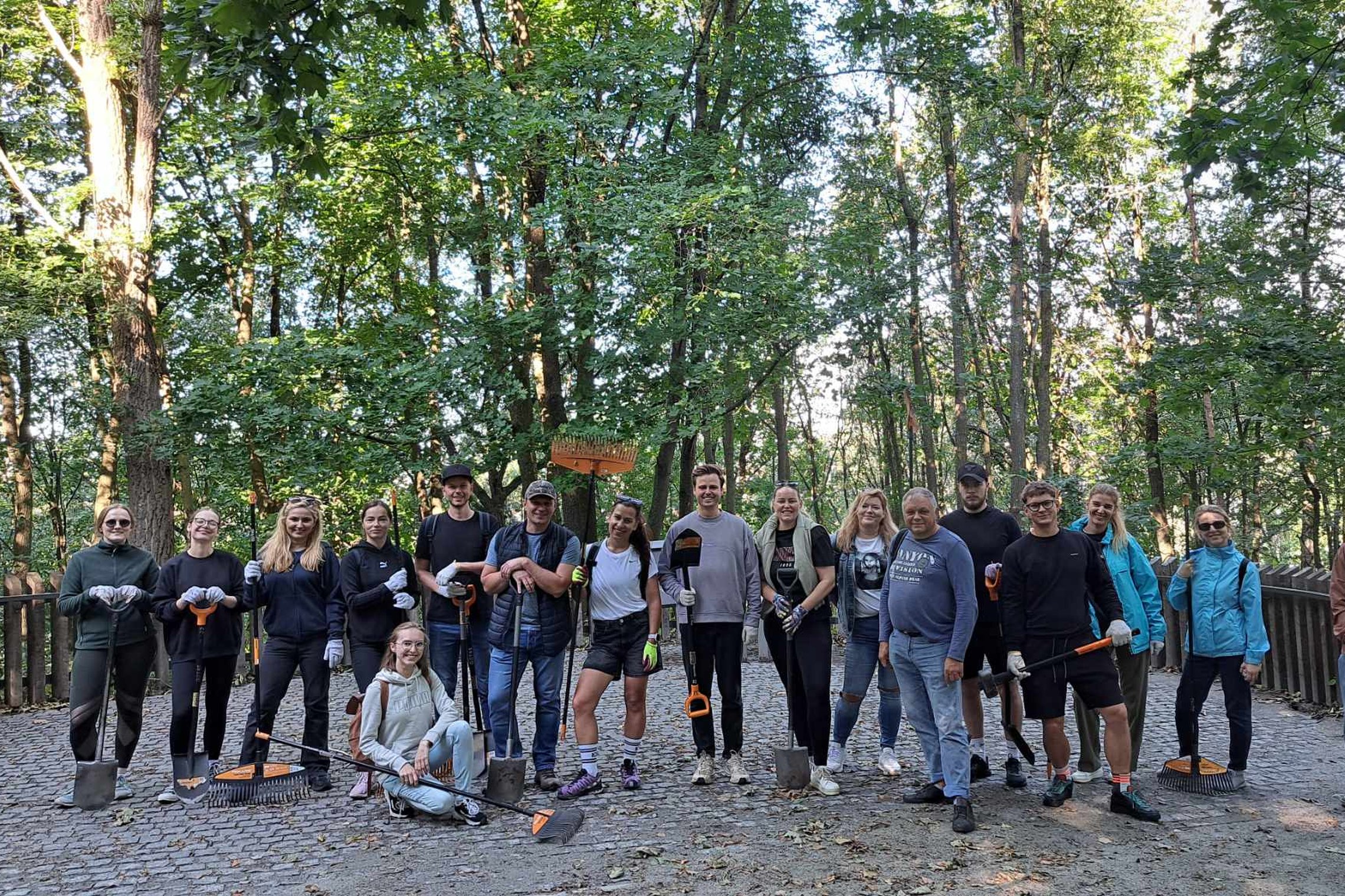 Gausi savanorių komanda su darbo įrankiais stovi Trijų Kryžių kalno atokvėpio aikštelėje.